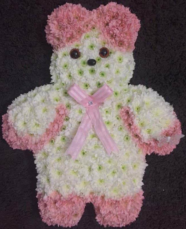 Floral teddy bear arrangement made of white and pink flowers, featuring black button eyes and a pink ribbon bow.
