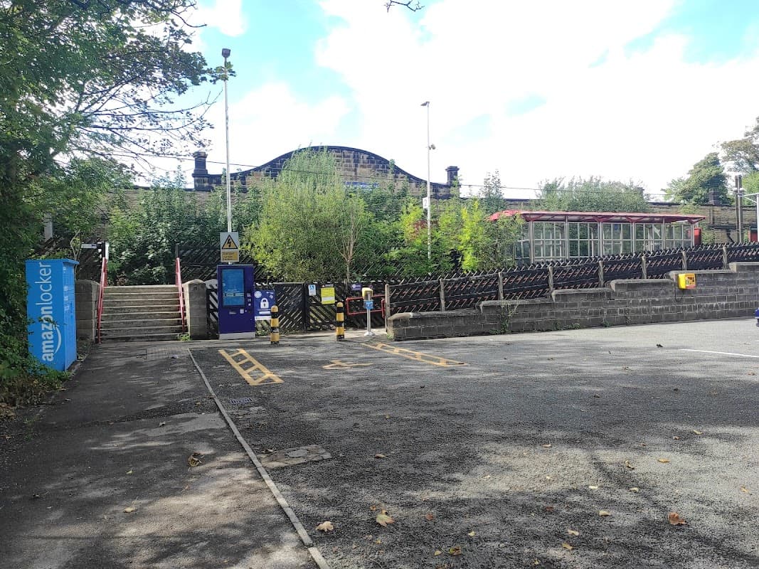 Frizinghall Station Car Park with parking spaces, greenery, and steps leading to the station entrance.