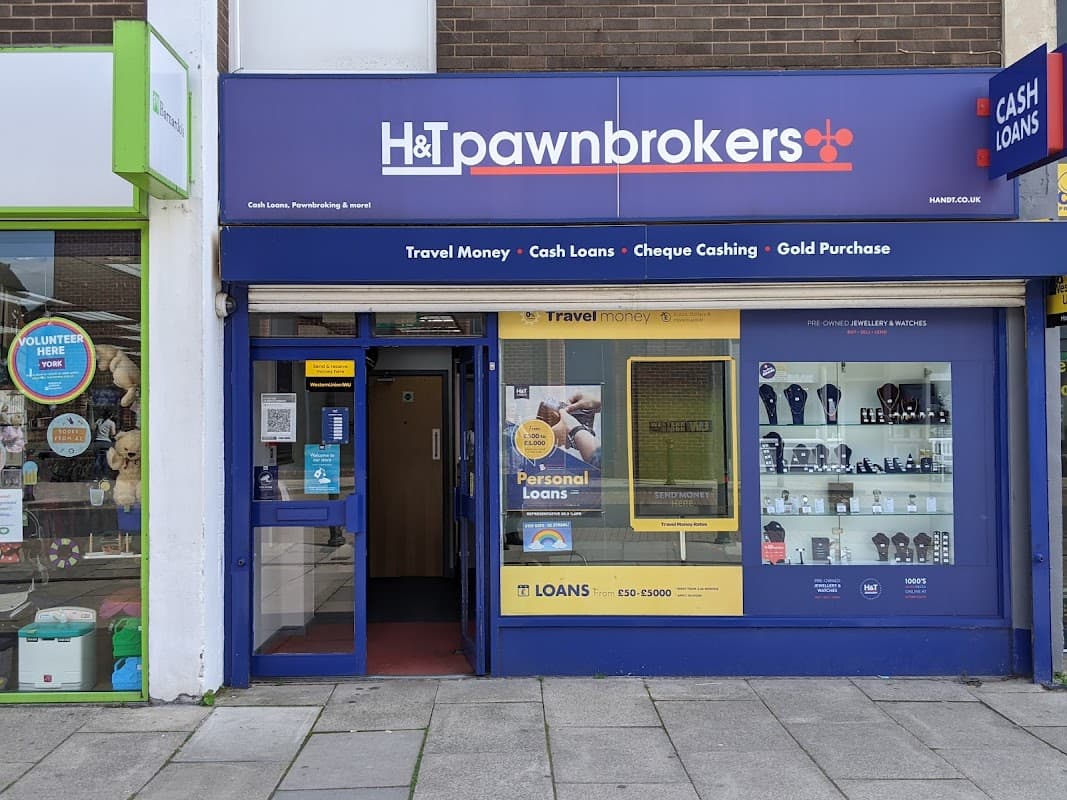 H&T Pawnbrokers storefront featuring signage for cash loans, travel money, and displays of jewelry and watches.