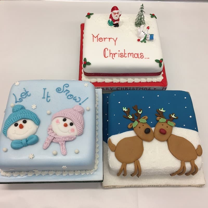 Three festive cakes: one with snowmen, one with a Santa and snowman, and another with reindeer, all decorated for Christmas.