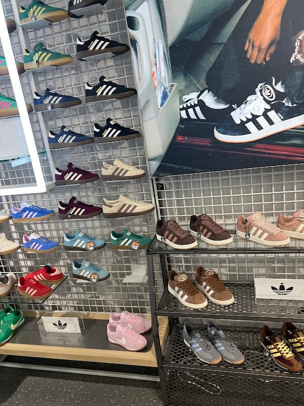 Colorful display of various Adidas sneakers on racks, showcasing different styles and colors in a retail setting.