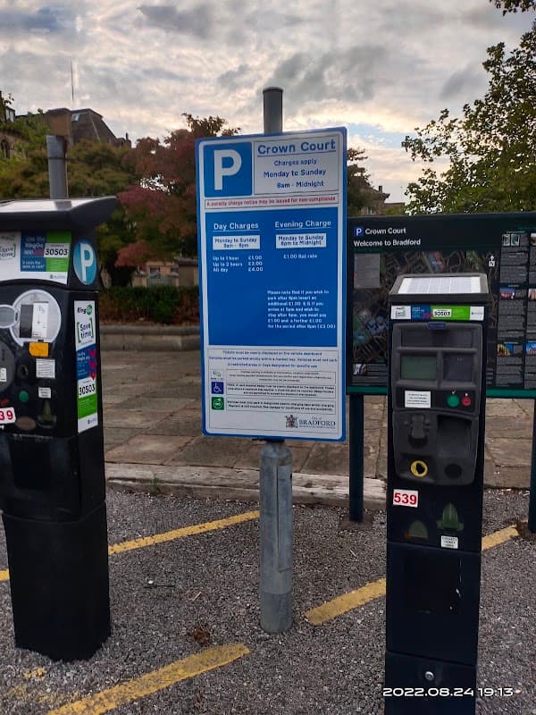 Pay & Display parking meters with a sign detailing charges at Crown Court car park in Bradford, Yorkshire.