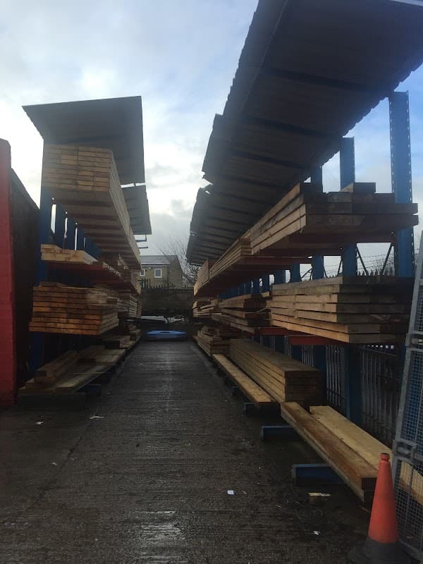Timber racks filled with wooden planks, lined along a pathway at Manningham Timber and Roofing in Bradford.