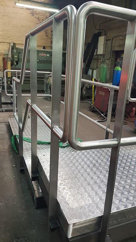 Metal railing on a raised platform with a textured surface, surrounded by industrial equipment in a workshop.