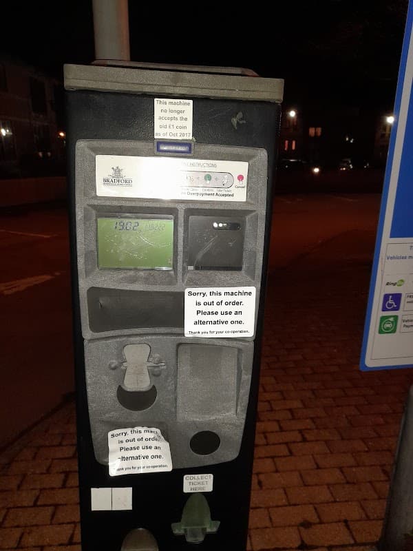 Pay & Display parking meter with multiple out-of-order notices and instructions, set in a car park at night.