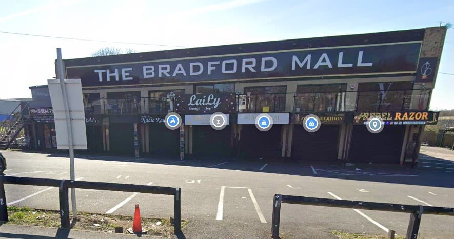 The Bradford Mall exterior with closed shops, parking spaces, and a sign for Pay & Display parking.
