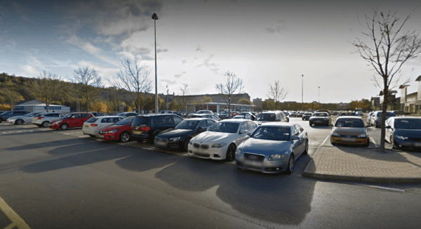 Pay & Display parking lot in Bradford, Yorkshire, filled with various parked cars and trees lining the area.