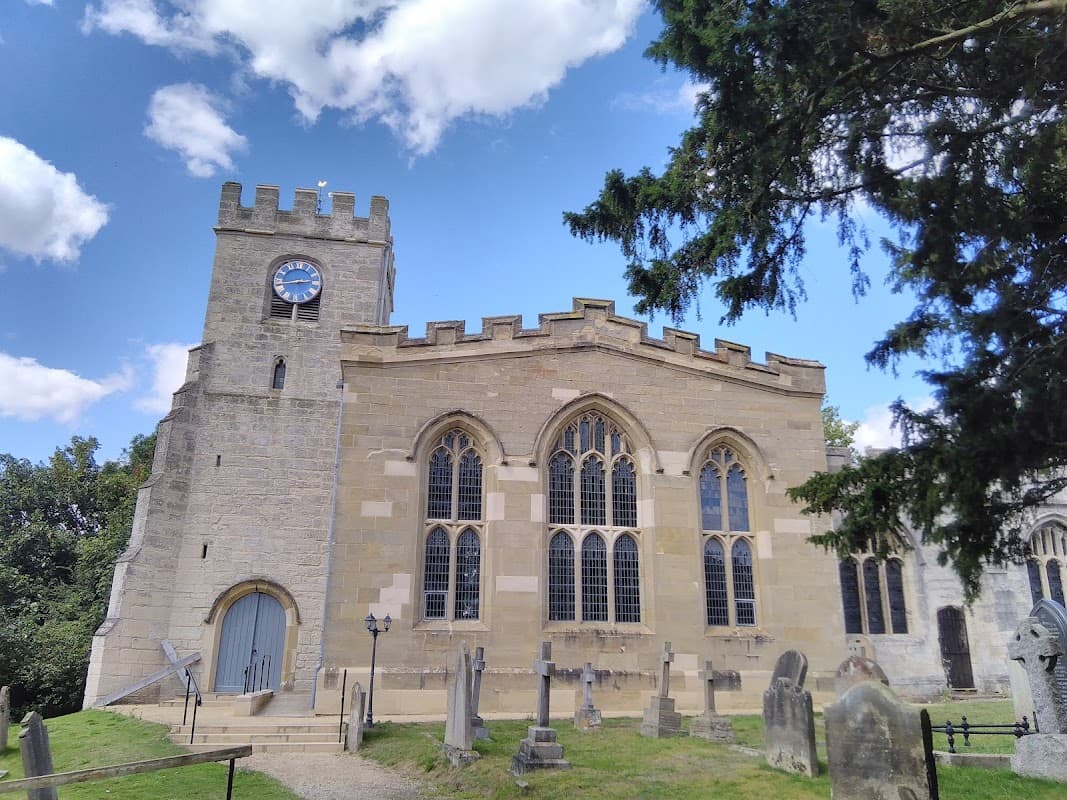 St Peter's Brafferton C of E V A Primary School, featuring stone architecture, a clock tower, and surrounding gravestones.