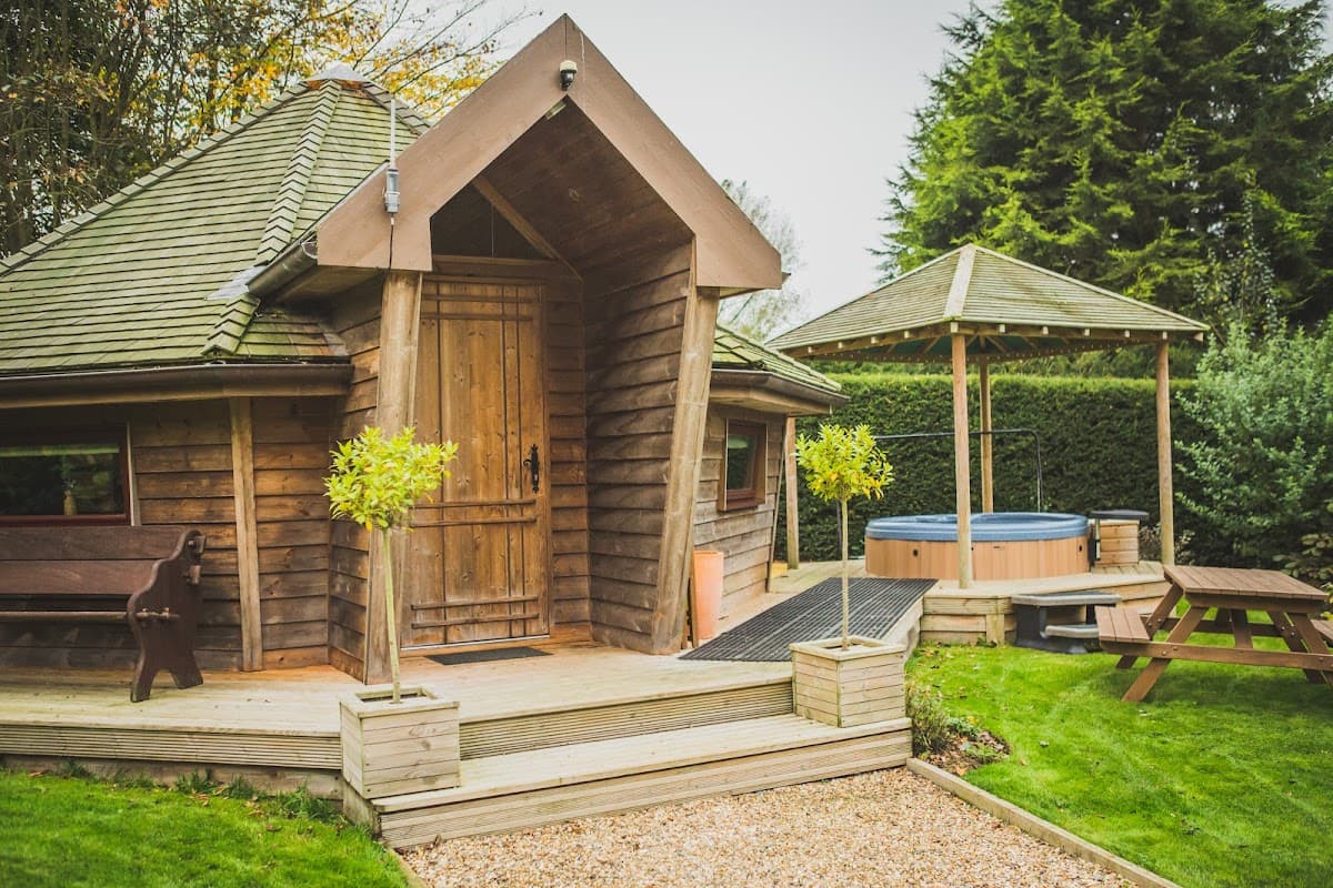 Cozy wooden lodge with a sloped roof, hot tub, picnic area, and lush greenery in Brandesburton, Yorkshire.