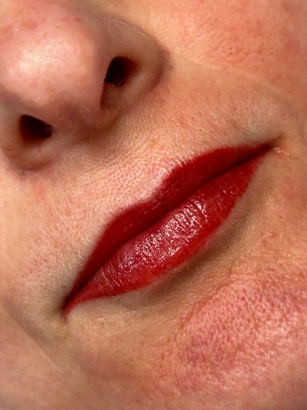 Close-up of lips with deep red lipstick, showcasing smooth skin and subtle texture.
