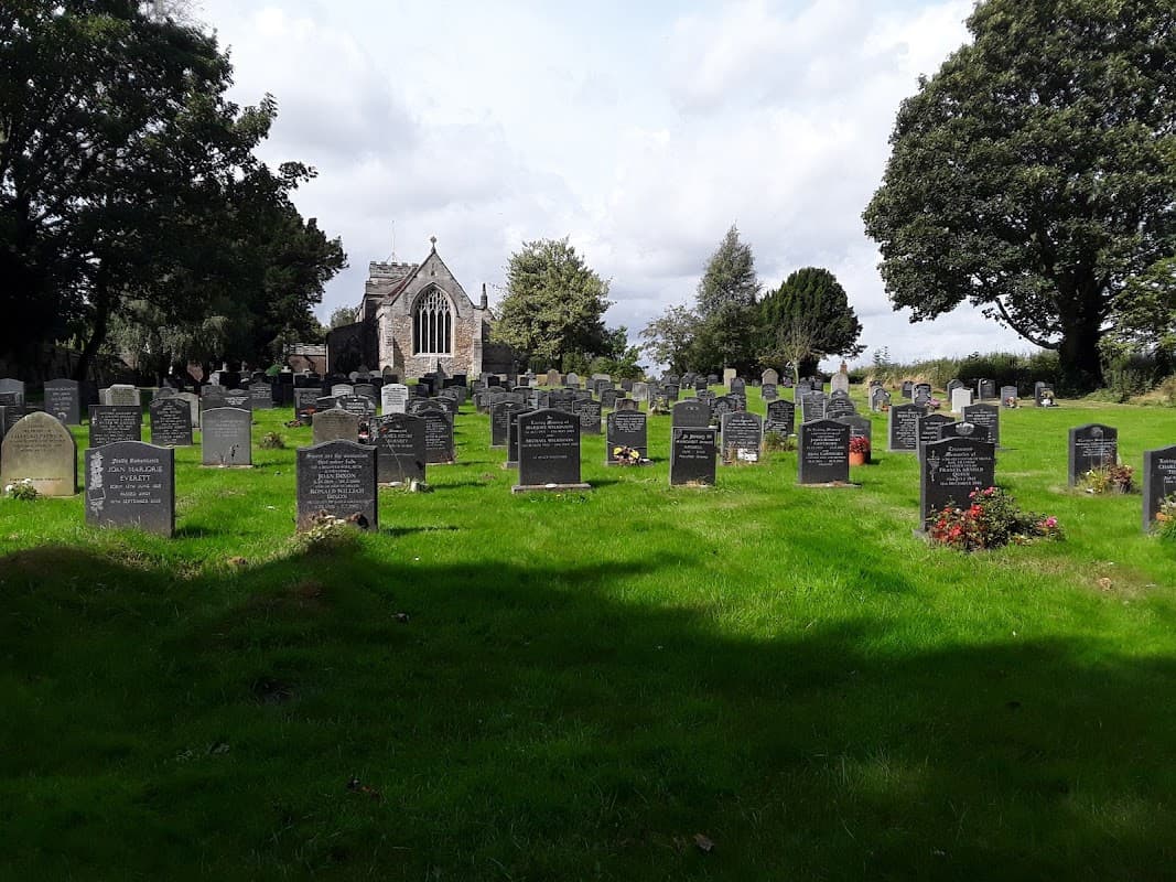 St Mary's Church surrounded by a lush graveyard filled with headstones under a cloudy sky.
