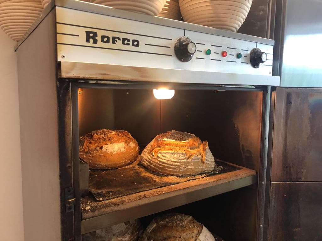 Rustic bread loaves baking in a Rofco oven, with warm light illuminating the crusty tops.