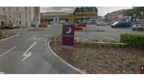 Parking lot with signs for Premier Inn, colorful cars, and landscaped areas in Bridlington, Yorkshire.