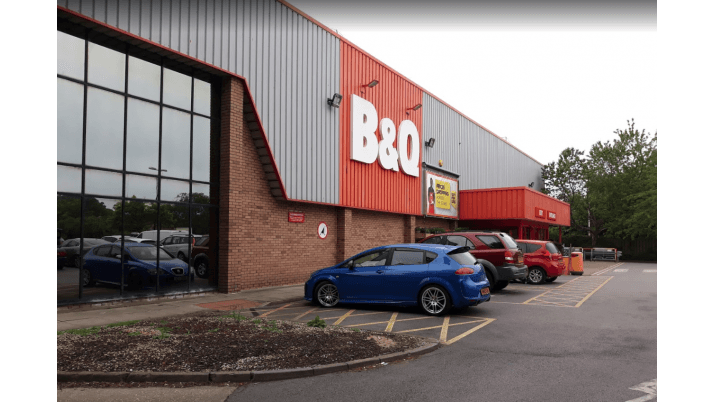 B&Q store exterior with parking area, featuring a blue car and several others, surrounded by greenery in Bridlington.
