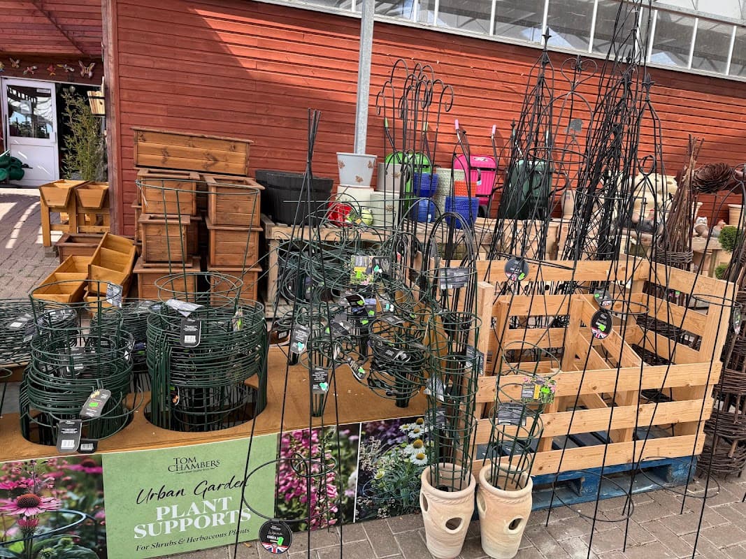 Plant supports and gardening supplies displayed on wooden pallets at Victoria Farm Garden Centre, surrounded by various pots.