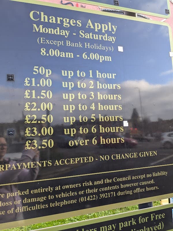 Sign detailing parking charges at Mill Lane Car Park, Brighouse, with hours and fees for various durations.