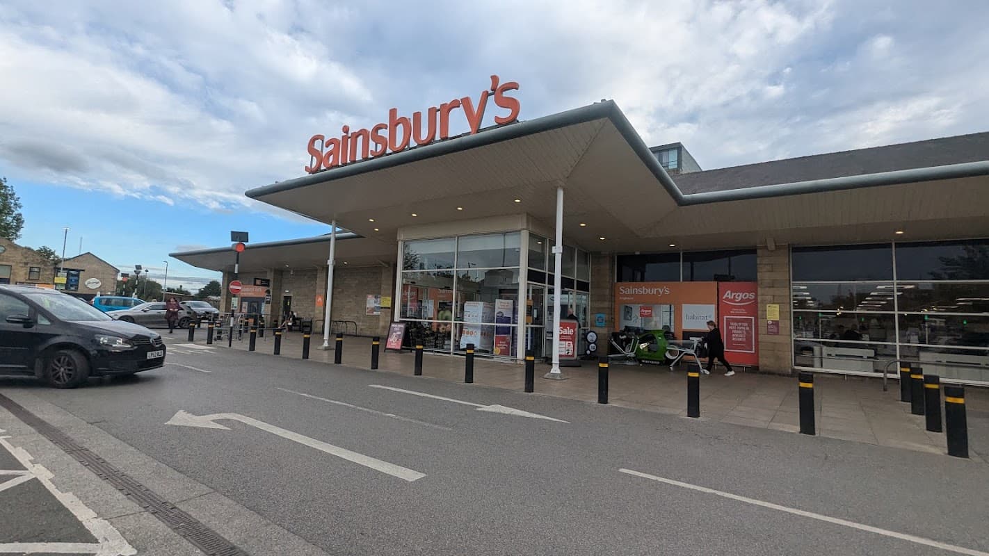 Sainsbury's store entrance in Brighouse, Yorkshire, with parked cars and signage visible.