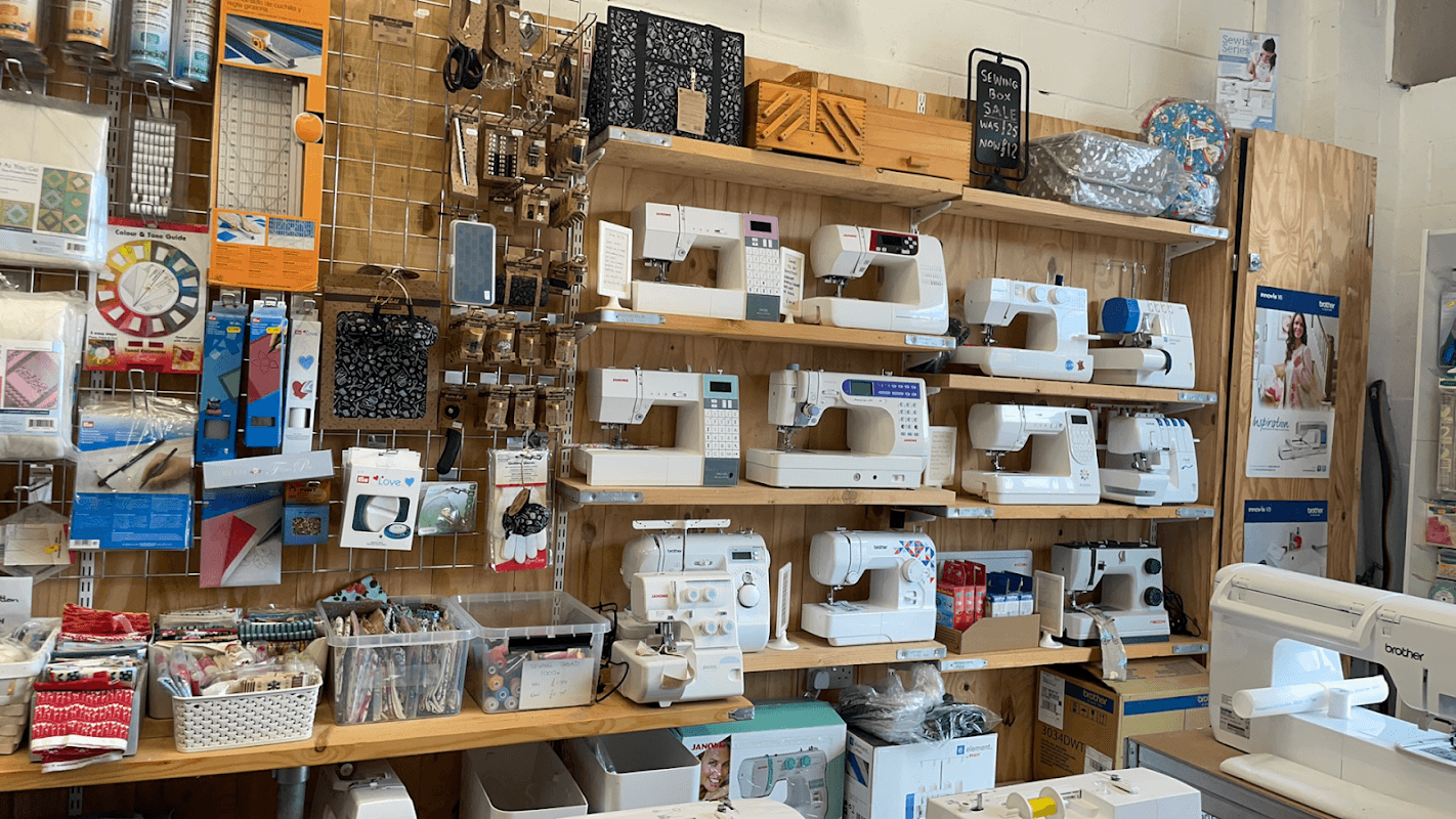 Sewing machines and crafting supplies displayed on wooden shelves in a cozy shop setting.