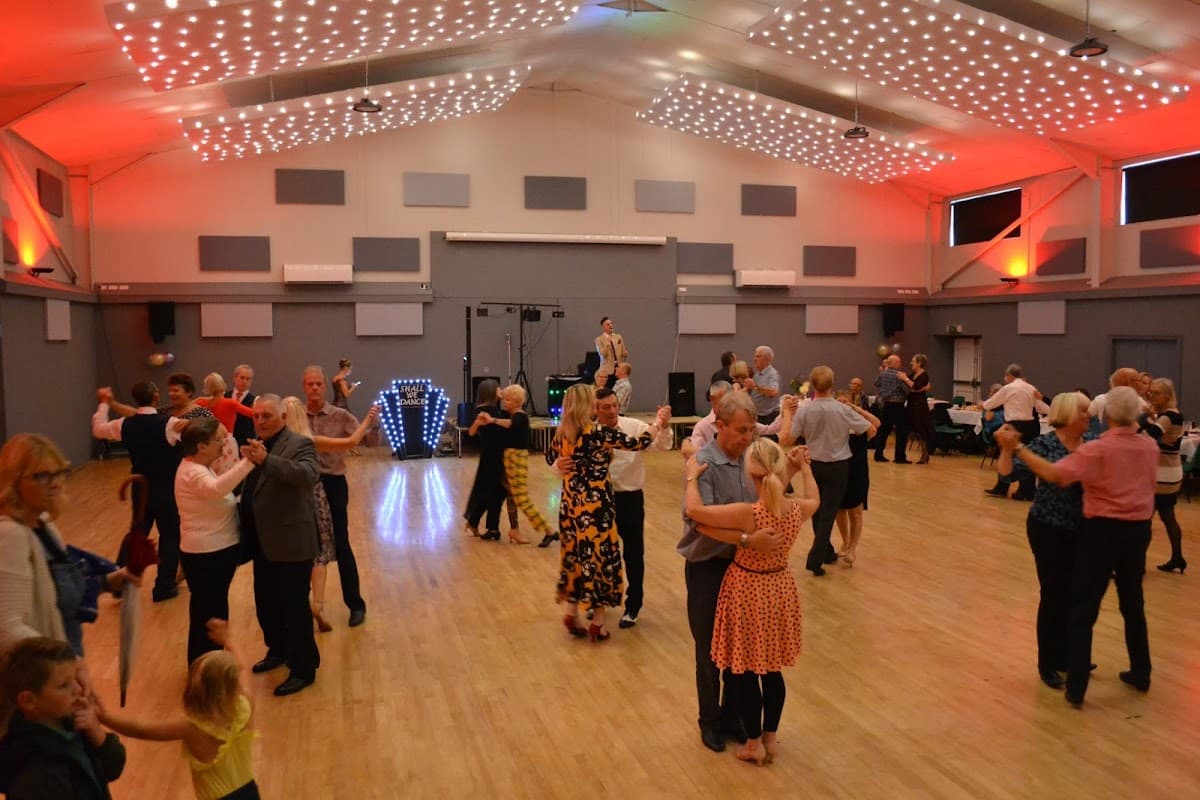 A lively dance event at Bubwith Leisure and Sports Centre, with people dancing under bright lights and a festive atmosphere.