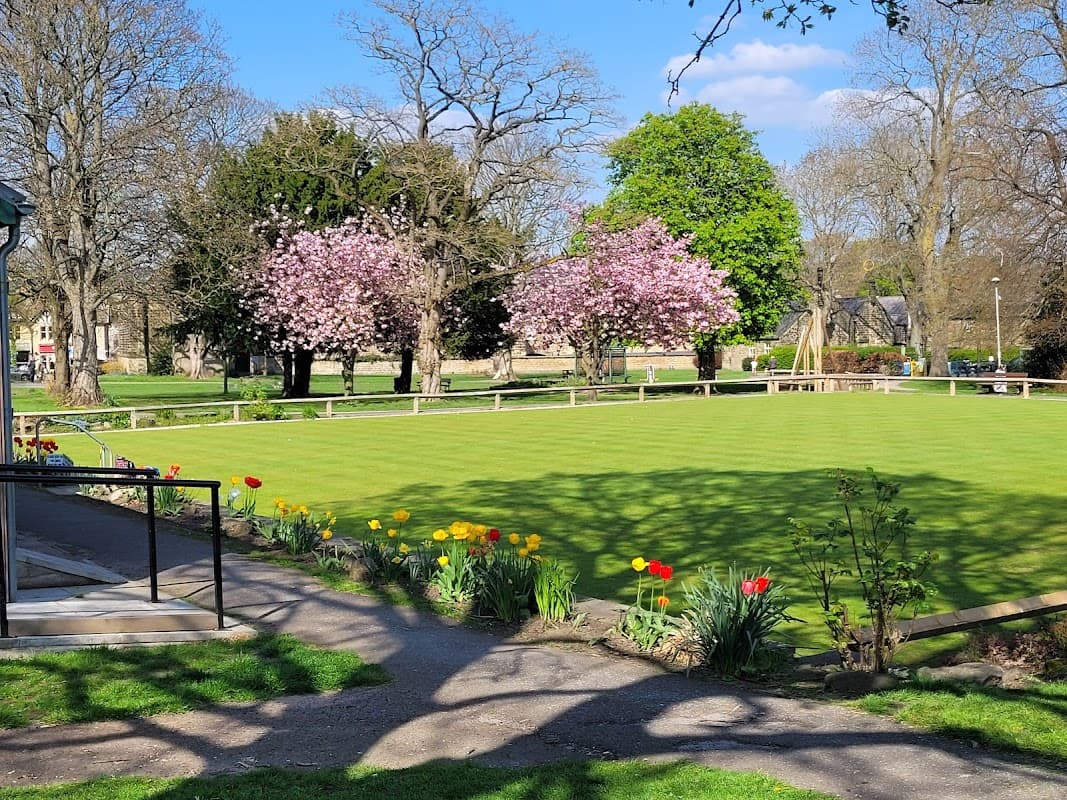 Lush green park with blooming cherry trees, colorful tulips, and a pathway leading to a bowling green in Burley.