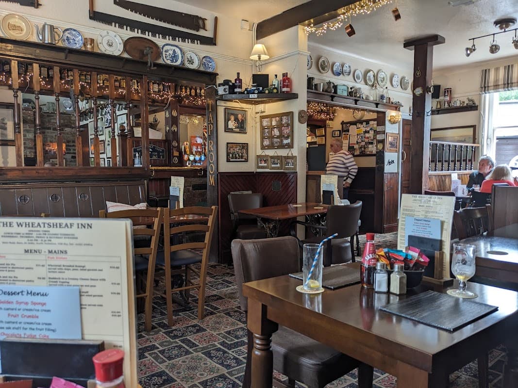 Cozy bar interior with wooden furniture, decorative plates, and patrons enjoying meals in a warm atmosphere.