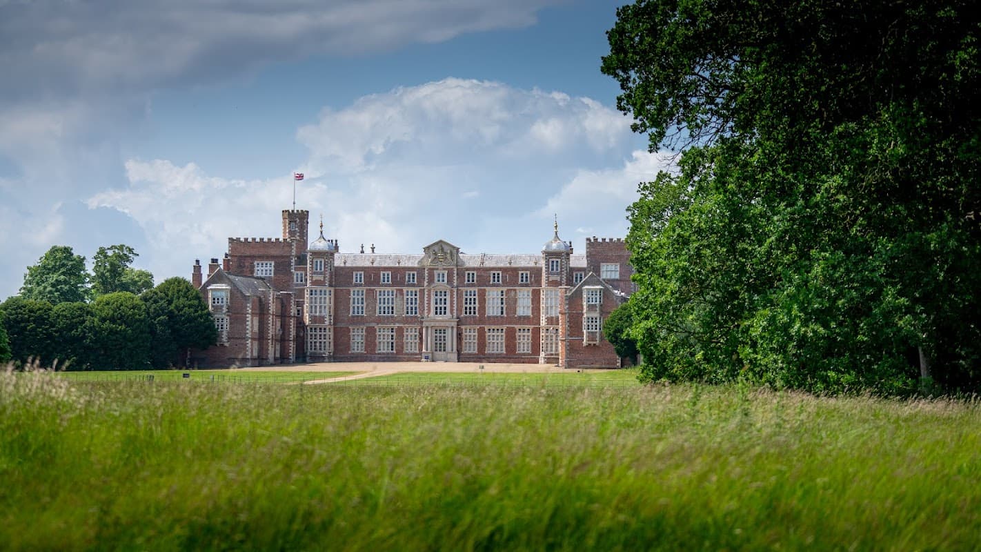Burton Constable Hall, a grand historic building, surrounded by lush parkland and under a partly cloudy sky.