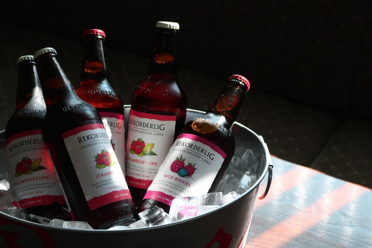 Five bottles of Rekorderlig cider in a bucket of ice, featuring strawberry-lime and wild berries flavors.