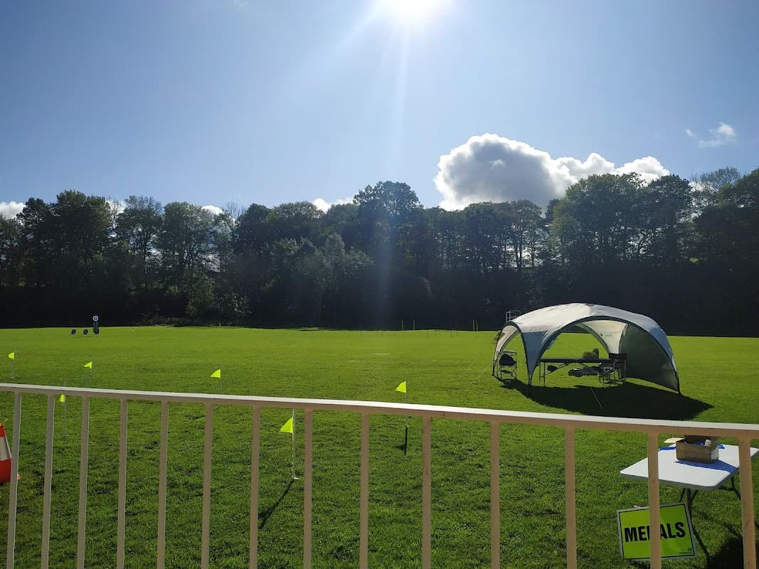 Bright sunny day at Lonsdale Sports Pavilion, featuring a green field, a tent, and flags marking the area.
