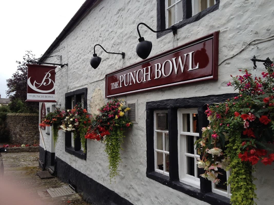 The Punch Bowl Inn features a whitewashed exterior, black trim, and vibrant flower baskets adorning the windows.