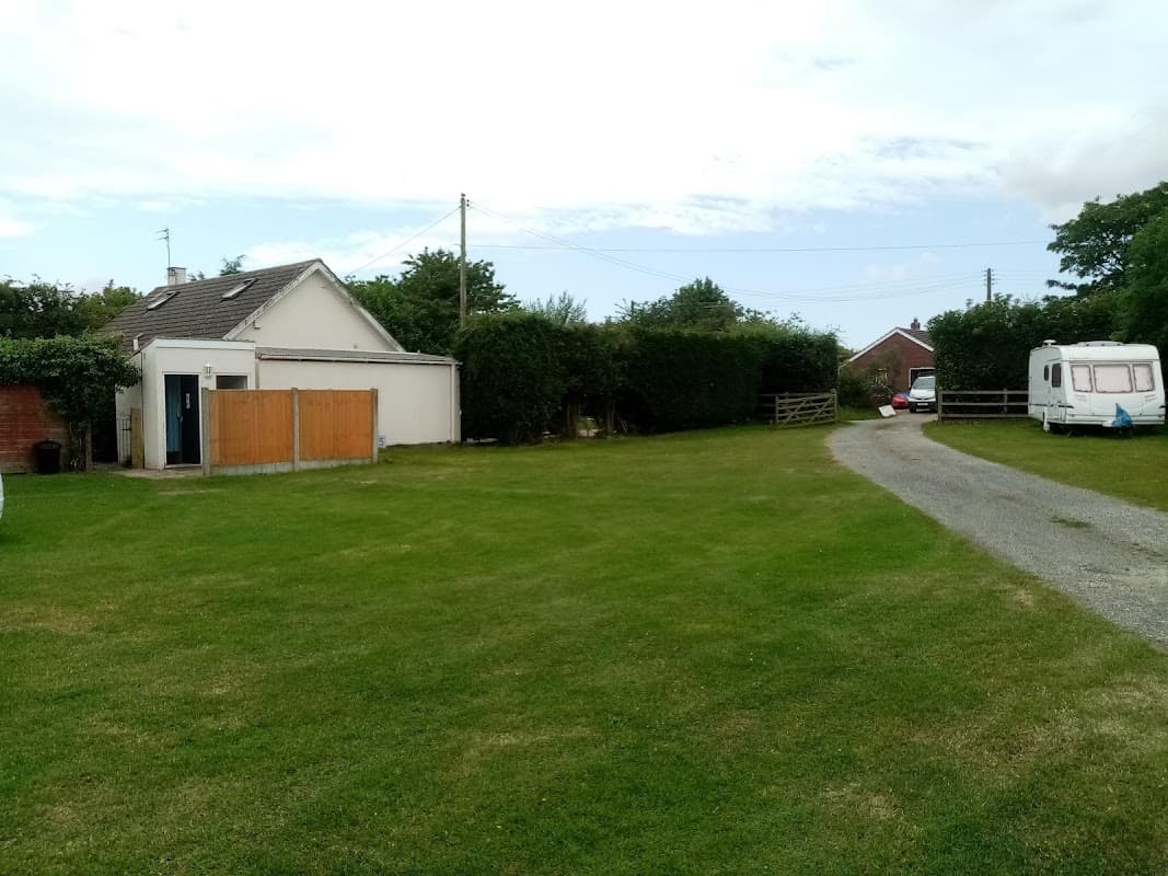 Hotel exterior with grassy area, gravel driveway, hedges, and a parked caravan in Burton Pidsea, Yorkshire.