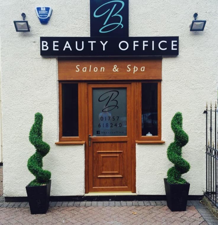 Sign for "Beauty Office" salon and spa, with decorative topiary plants flanking the entrance in Camblesforth, Yorkshire.