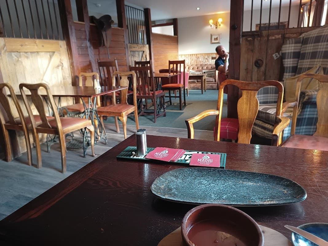 Cozy interior of Comus Inn with wooden furniture, a table setting, and a glimpse of patrons in the background.