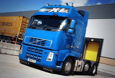 Blue Volvo truck with "Max International Transport Ltd" signage parked near a loading dock in Camblesforth, Yorkshire.