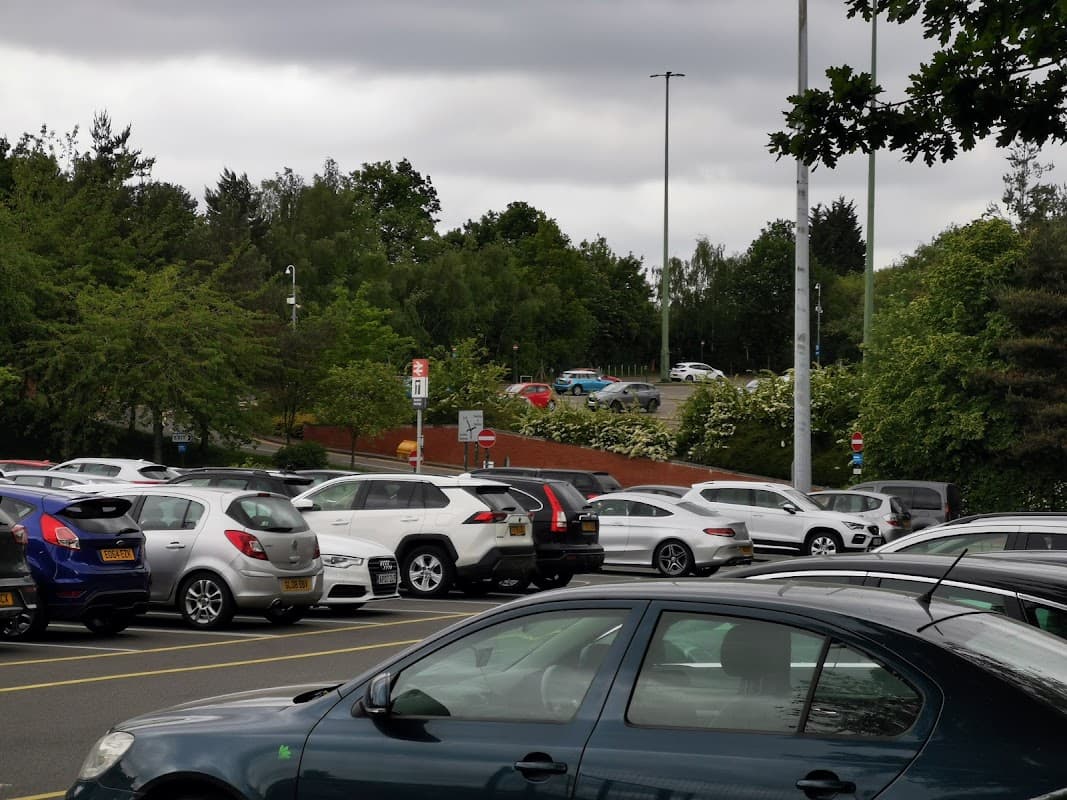 Park and Ride facility with numerous parked cars, green trees, and a cloudy sky in Carbrook, Yorkshire.