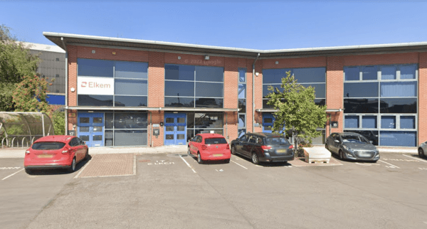 Pay & Display parking area with several cars outside a modern brick building featuring blue doors and signage.