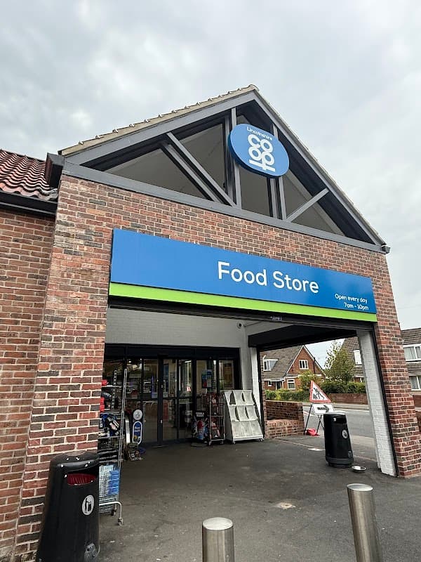 Entrance of Lincolnshire Co-op Carlton Food Store with a blue sign and brick facade, featuring shopping carts outside.