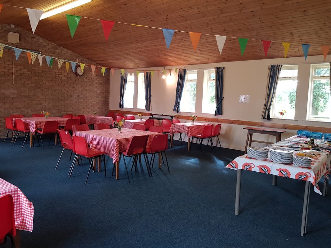 Brightly decorated hall with red checkered tables, colorful bunting, and floral centerpieces.