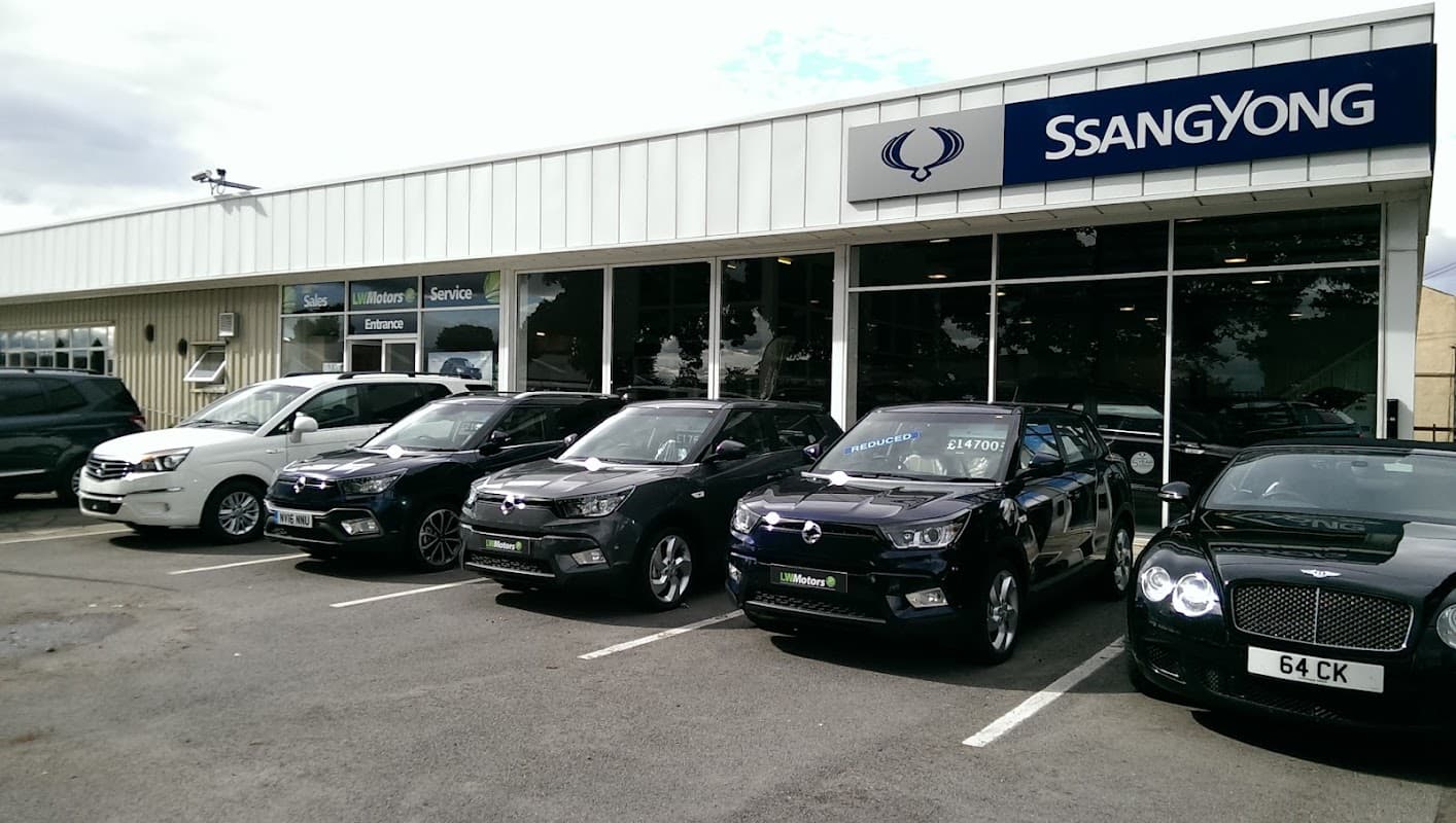 Showroom with multiple SsangYong vehicles parked outside, featuring a large glass front and signage for sales and service.