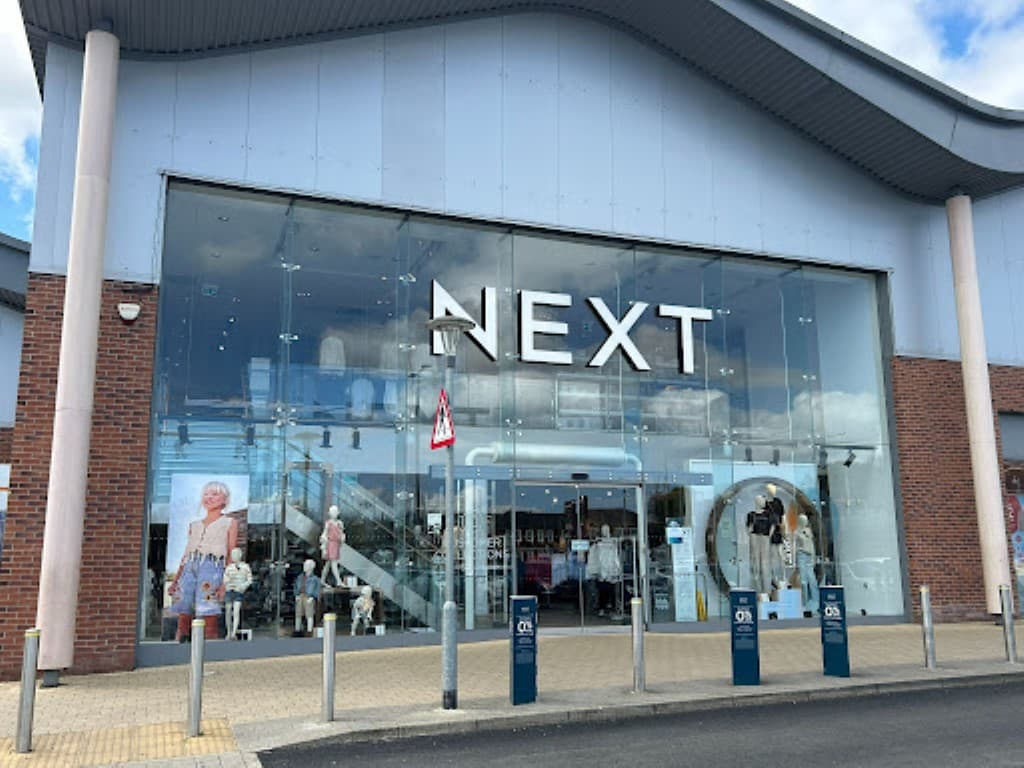 Large glass storefront of Next shop with mannequins displaying clothing, located in Catterick Garrison, Yorkshire.