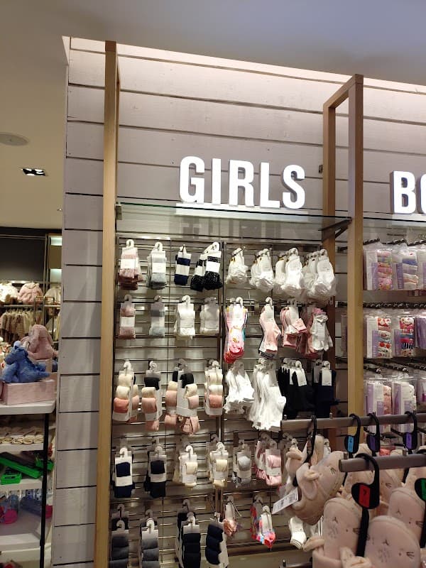 Display of girls' clothing and accessories on shelves, featuring various colors and styles in a retail setting.