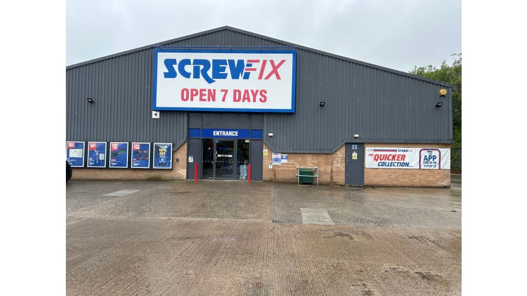 Screwfix store exterior with a large sign, entrance doors, and promotional posters in Catterick Garrison, Yorkshire.