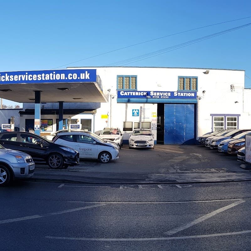 Catterick Service Station with multiple cars parked outside and a blue building featuring a large entrance.