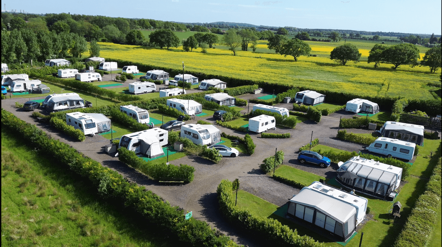 Holiday lodges and seasonal pitches in a lush green landscape, surrounded by fields and trees in Cawood, Yorkshire.