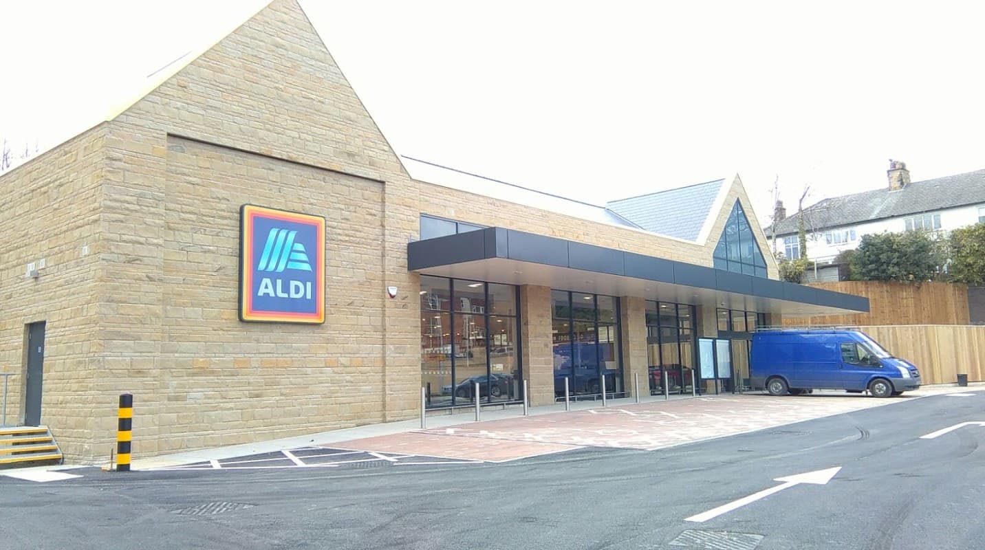 ALDI store in Chapel Allerton, Yorkshire, featuring a stone facade and large glass entrance, with a blue delivery van parked outside.