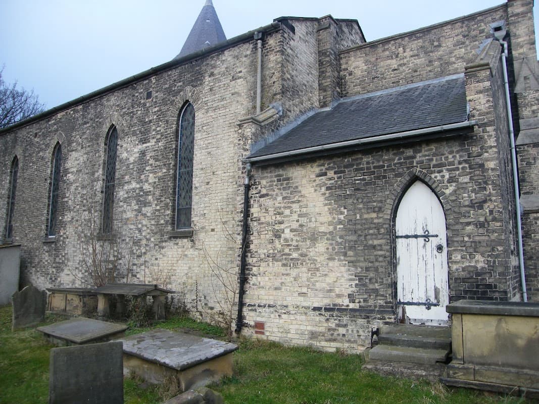 St John the Baptist Church features a stone exterior, arched windows, a white door, and adjacent gravestones.