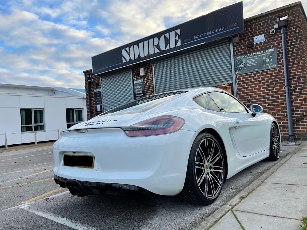 A sleek white sports car parked outside Source Sounds, a tech shop with a brick exterior and signage in Chapeltown.