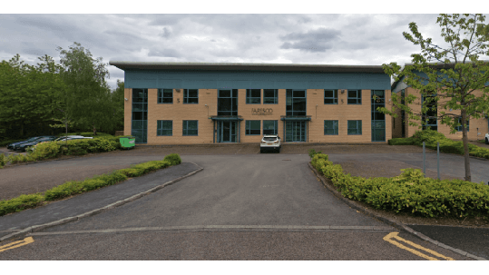 Parking area with a large building, trees, and several parked cars in Chapeltown, Yorkshire.