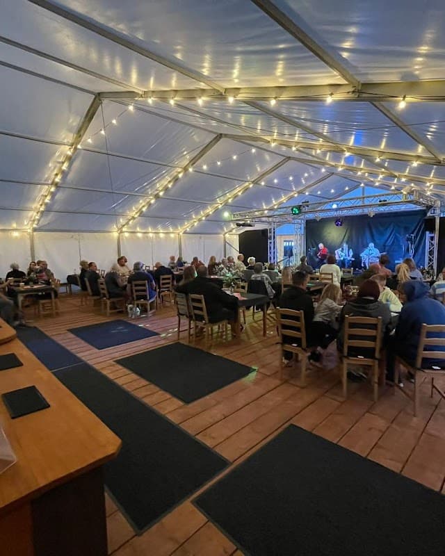 A lively indoor event at The Pearl and Oyster, featuring guests seated at tables under fairy lights.