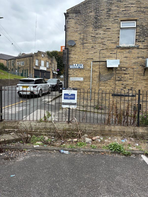 Private car park sign in Clayton, Yorkshire, with parked cars and a stone building in the background.
