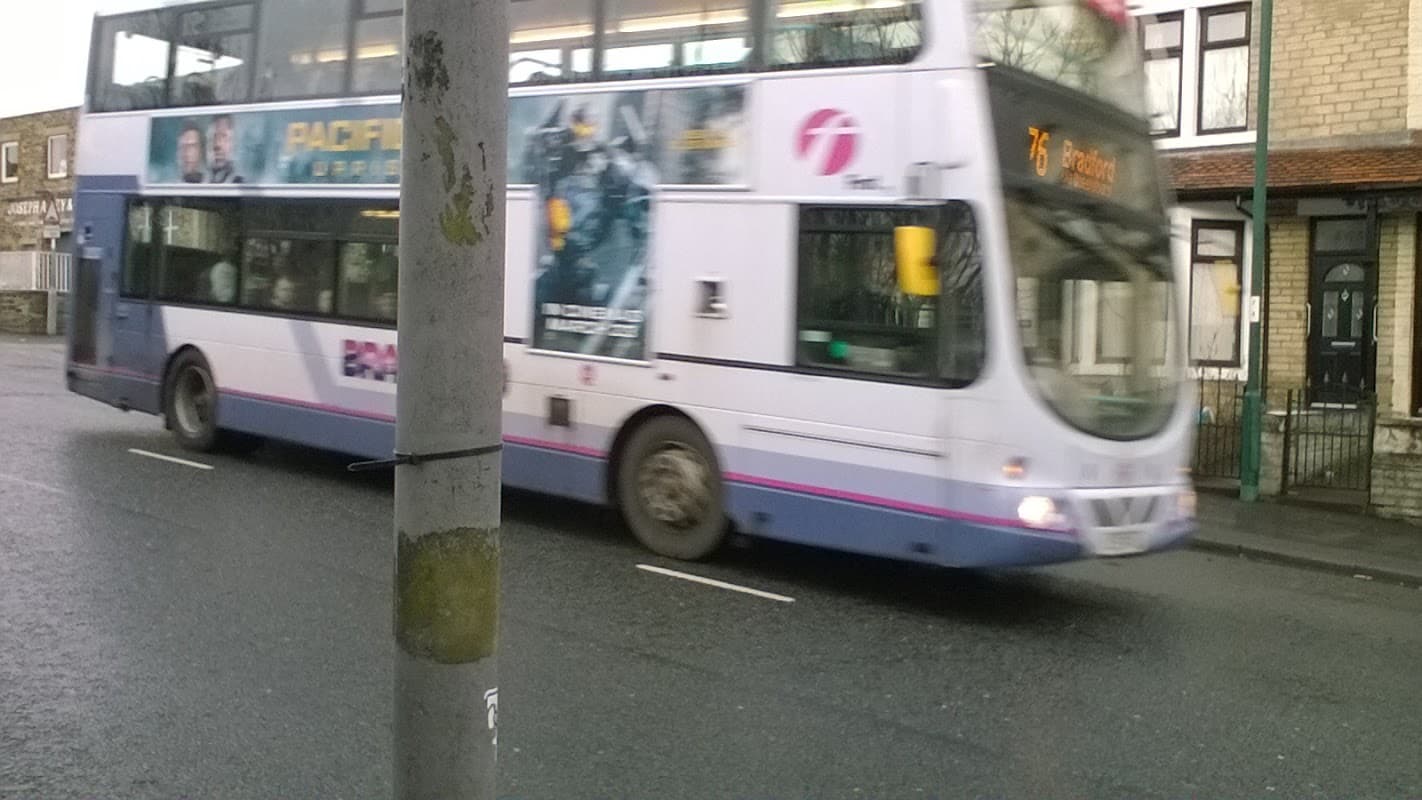 A blurred double-decker bus passes by a street pole near Horton Park Avenue in Clayton, Yorkshire.